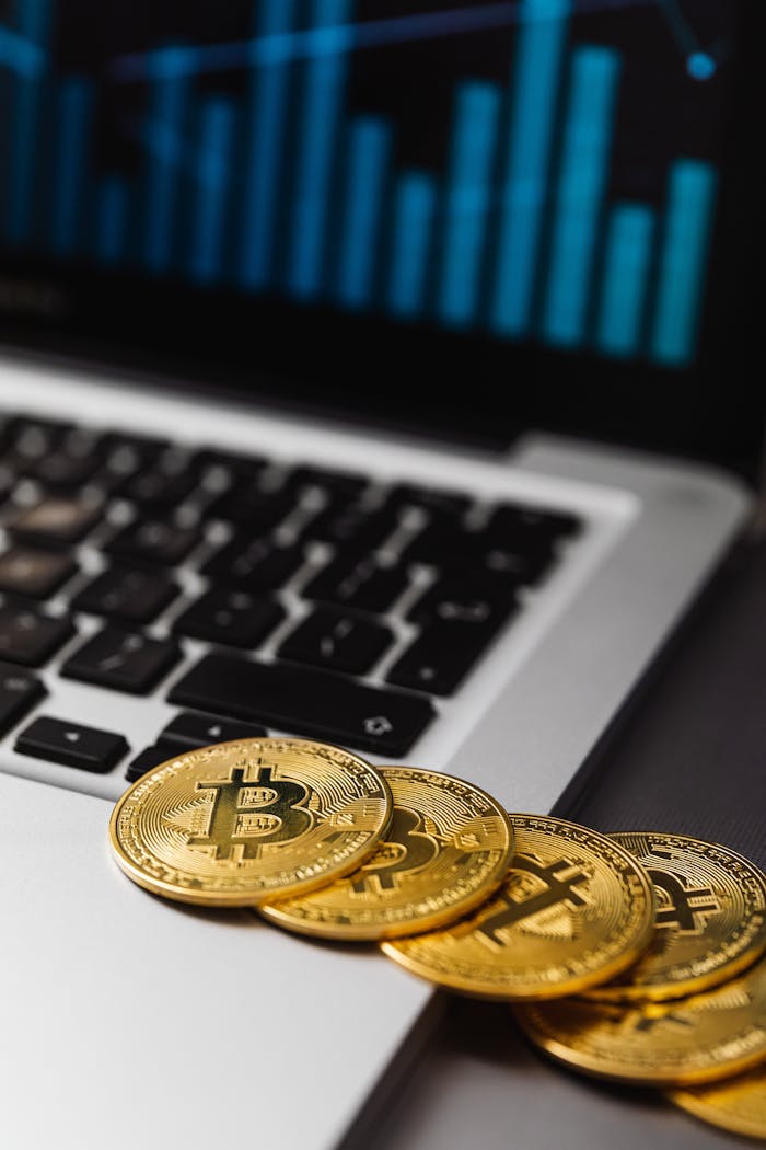 Close-up of gold Bitcoins on an open laptop with financial graph, symbolizing cryptocurrency and digital finance trends.